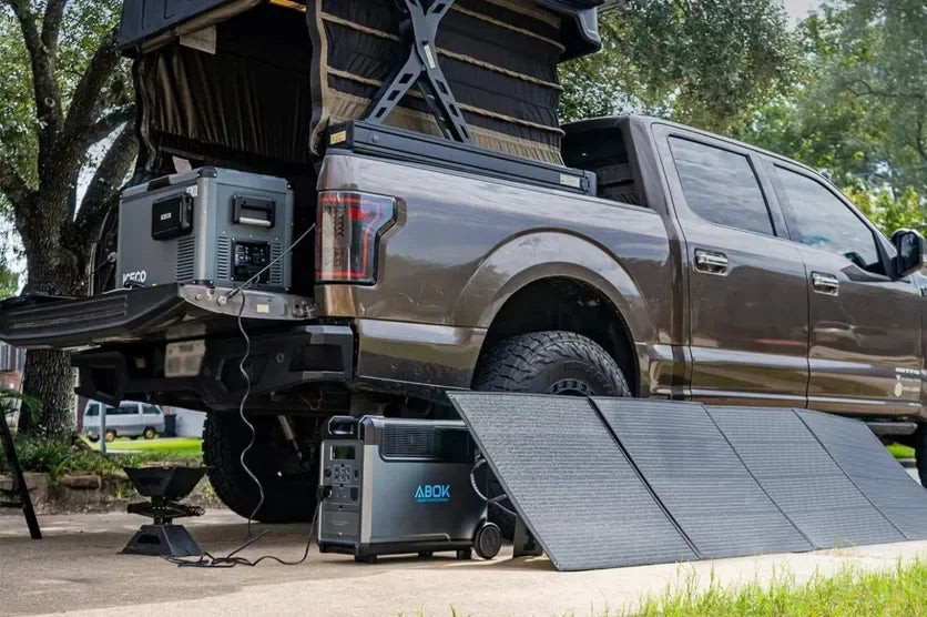 ABOK Ark Series portable power stations and foldable solar panels at a truck campsite.